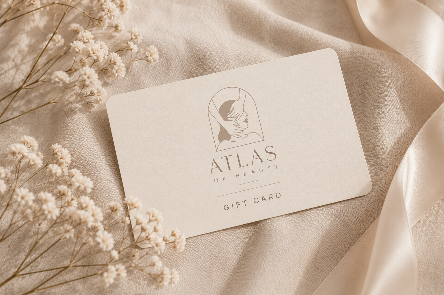 Atlas of Beauty gift card on cream linen with dried florals
